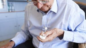 Senior Man At Home Using Distress Alarm Call Button